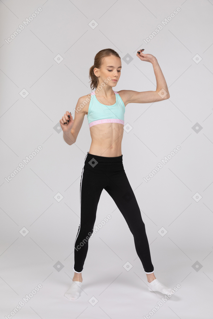 Vista di tre quarti di una ragazza adolescente in abiti sportivi a piedi e alzando il braccio
