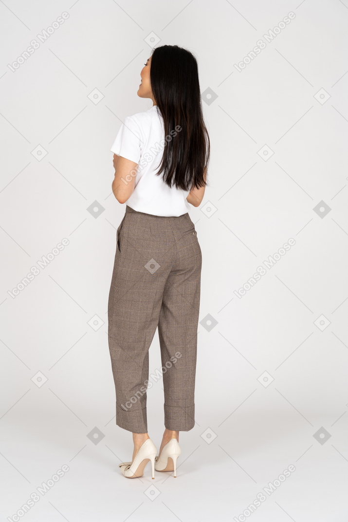 Three-quarter back view of a pleased young lady in breeches and t-shirt holding hands together