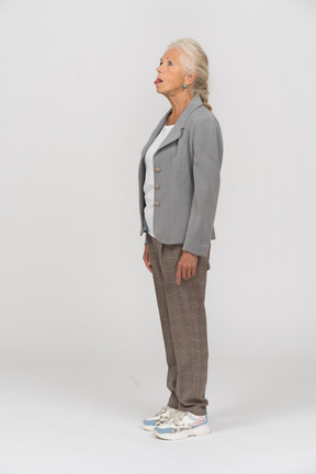 Side view of an old lady in suit showing tongue