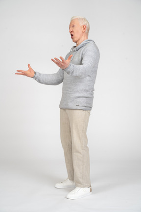Vista di tre quarti di un uomo in piedi con la bocca aperta e tenendo le mani in alto