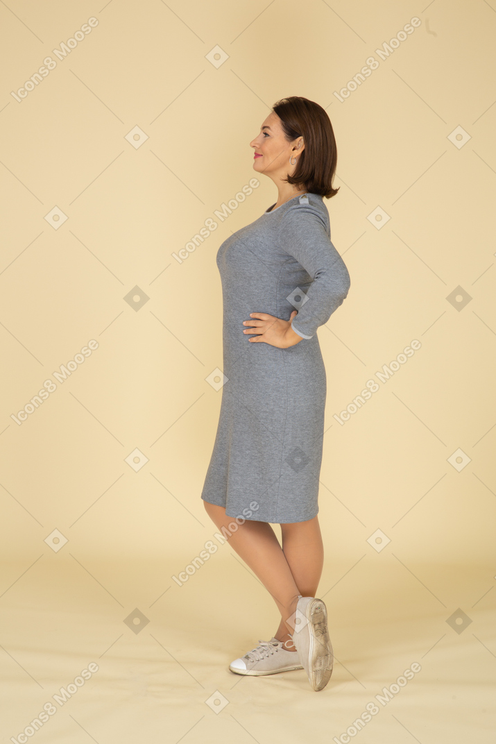 회색 드레스 포즈를 취하는 여자의 측면보기