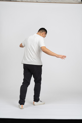Back view of a man in casual clothes walking with outstretched arms