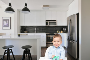 A baby sitting in a high chair in a kitchen