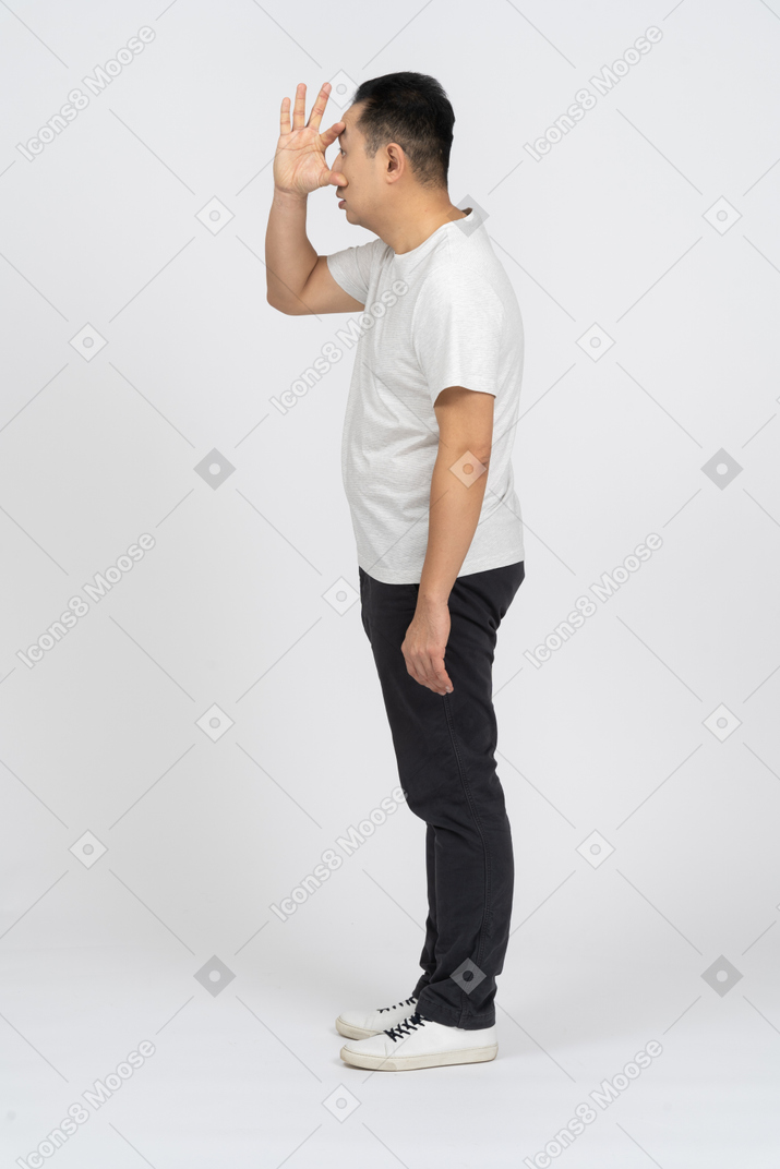 Vue latérale d'un homme en vêtements décontractés regardant à travers les doigts