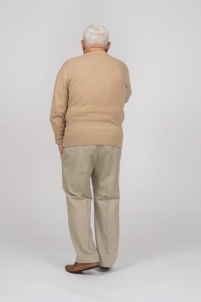 Rear view of an old man in casual clothes walking