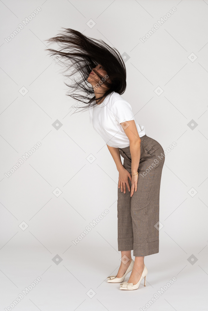 Vista de três quartos de uma jovem de calça e camiseta com cabelo bagunçado