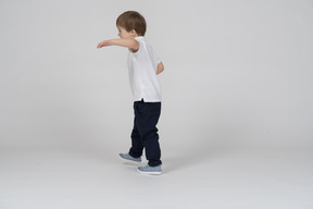 Three-quarter back view of a boy raising hand in a half-hug