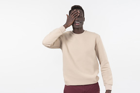 Un giovane uomo di colore in un maglione grigio in piedi da solo su sfondo bianco
