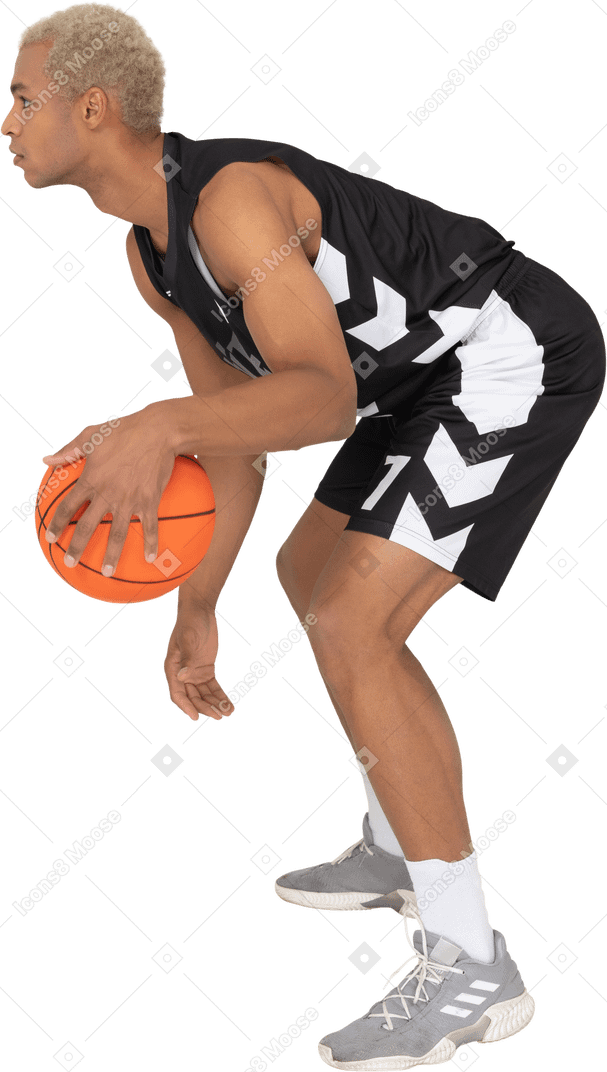 做运球的一名年轻男性篮球运动员的侧视图