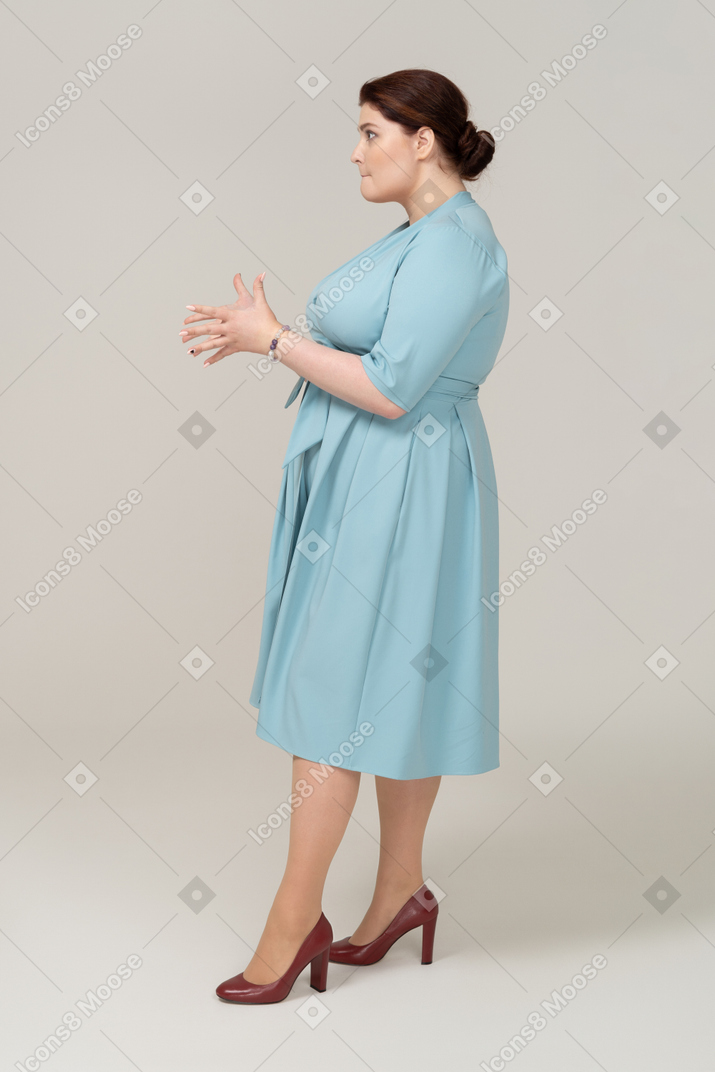 Vista lateral de uma mulher de vestido azul fazendo caretas