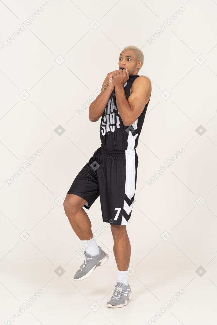 Vista de tres cuartos de un joven jugador de baloncesto masculino asustado reclinado hacia atrás