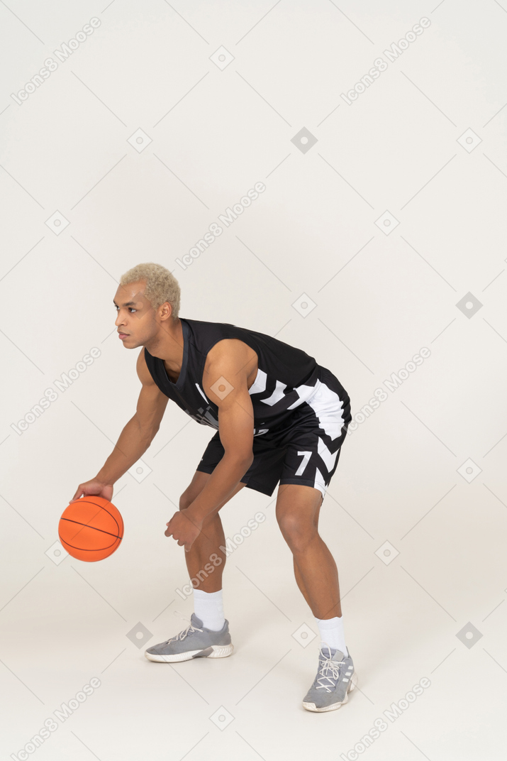 Three-quarter view of a young male basketball player doing dribbling