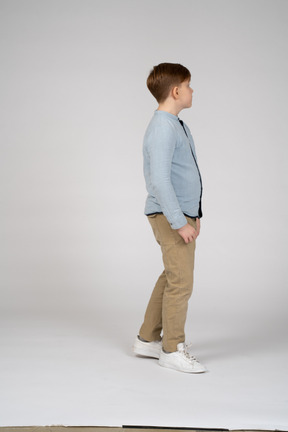 一个穿着蓝色衬衫的站立男孩的侧视图