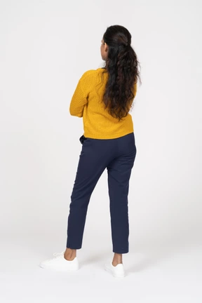 Rear view of a girl in casual clothes posing with crossed arms