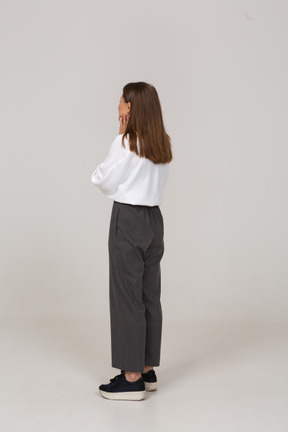 Vista posteriore di tre quarti di una giovane donna in abiti da ufficio che tocca il viso