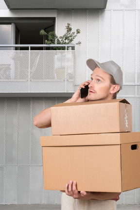 A man is holding a box and talking on a cell phone