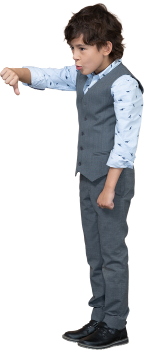 Vue latérale d'un garçon en costume gris montrant le pouce vers le bas