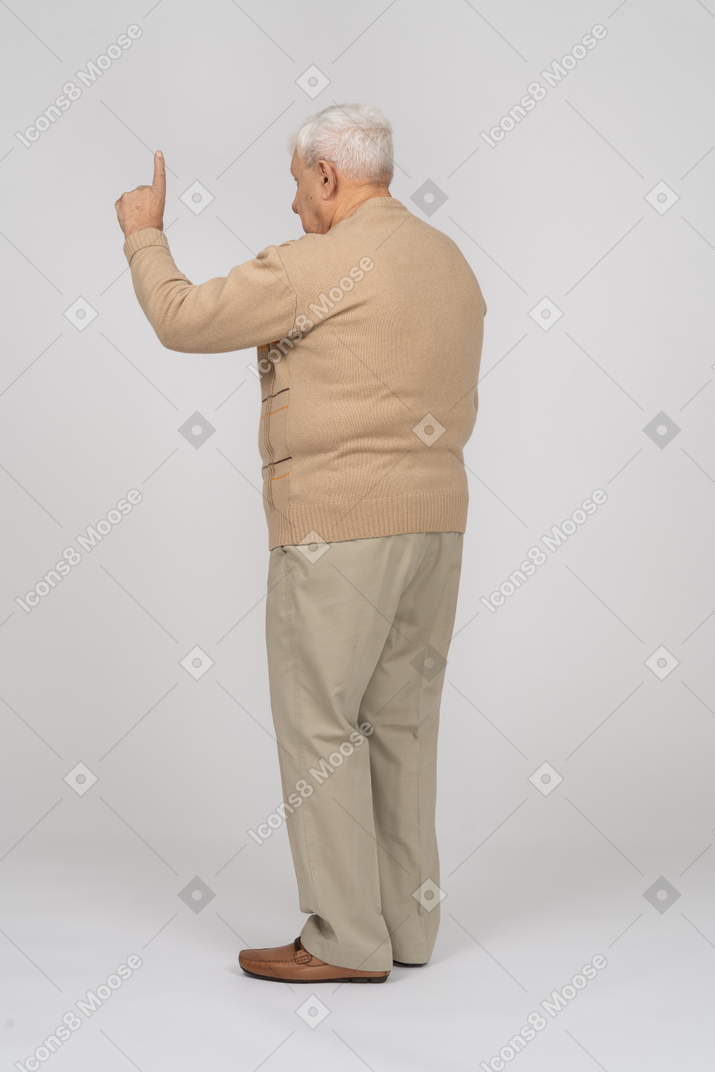 Vista lateral de um velho em roupas casuais apontando para cima com um dedo