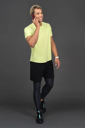 Front view of a dark-skinned young man having a phone call