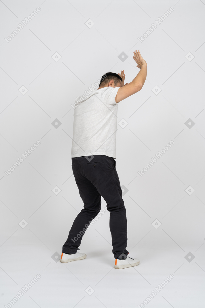 Вид сбоку на мужчину в повседневной одежде, стоящего с поднятыми руками