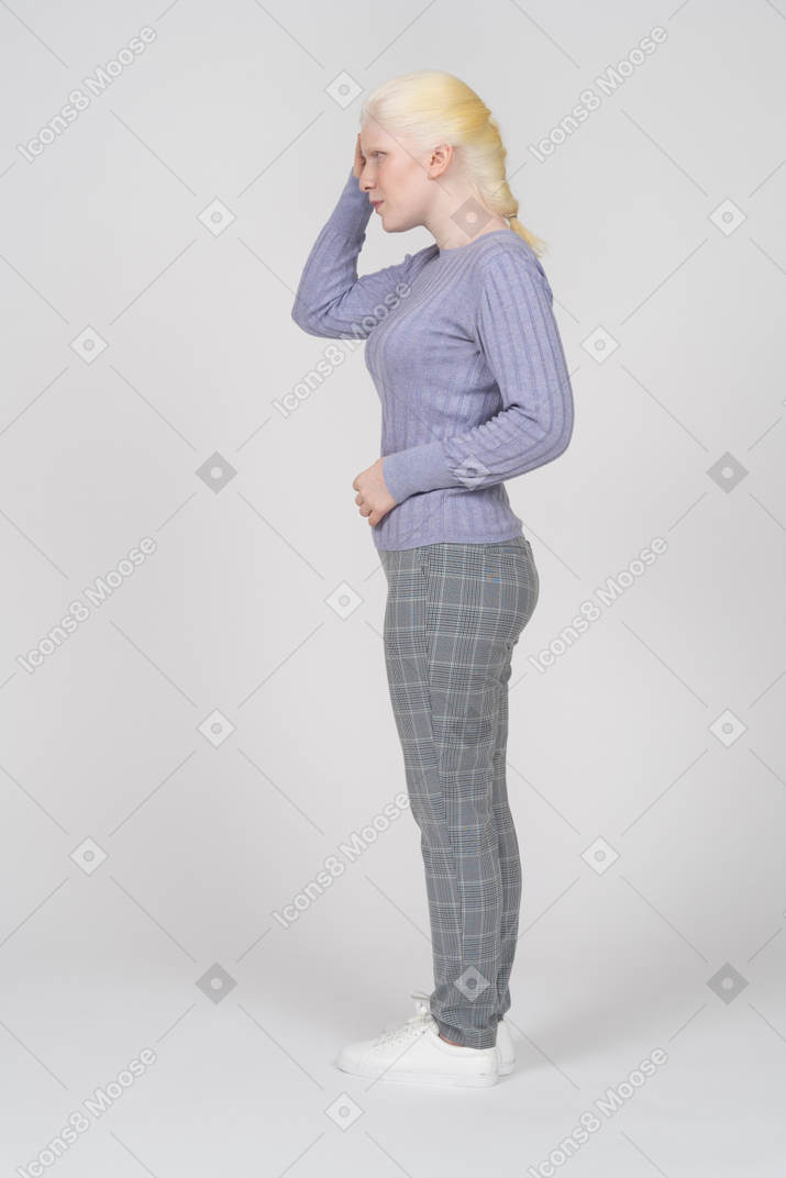 Vista lateral de uma mulher em roupas casuais, tocando o lado da cabeça