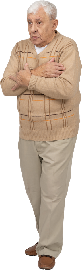 Vista frontal de un anciano asustado con ropa informal de pie con las manos en el pecho
