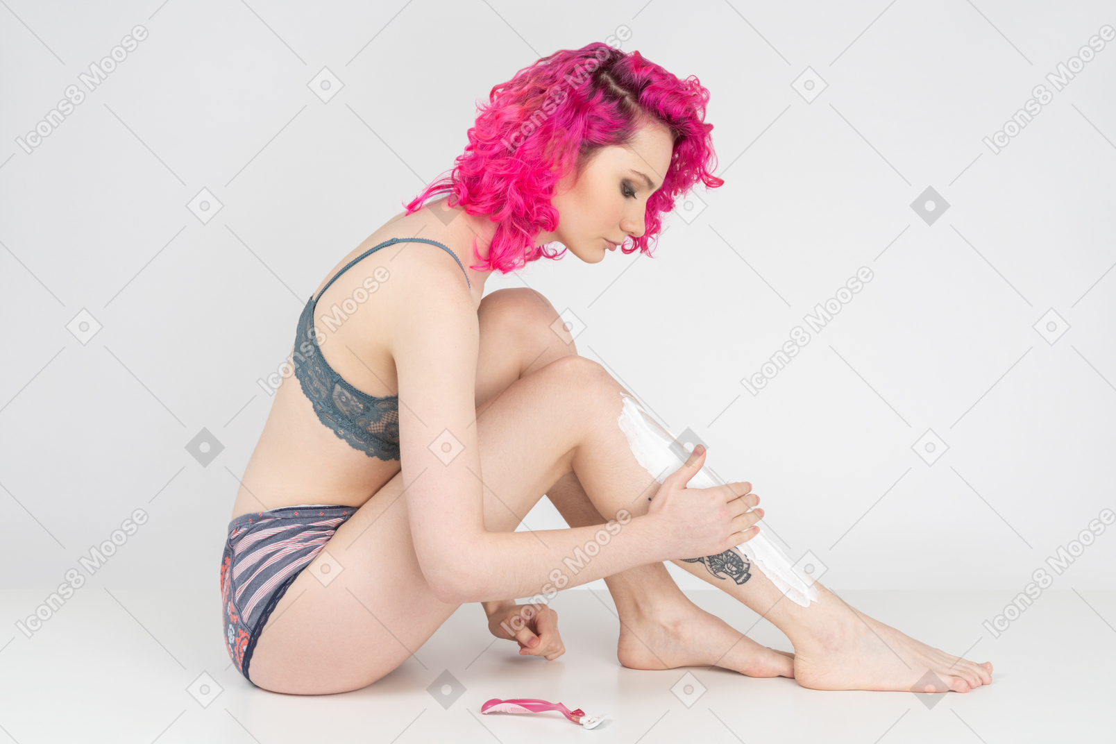 Young woman sitting on the floor and applying shaving cream