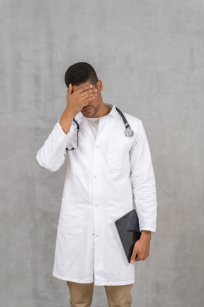 Overworked doctor covering his face
