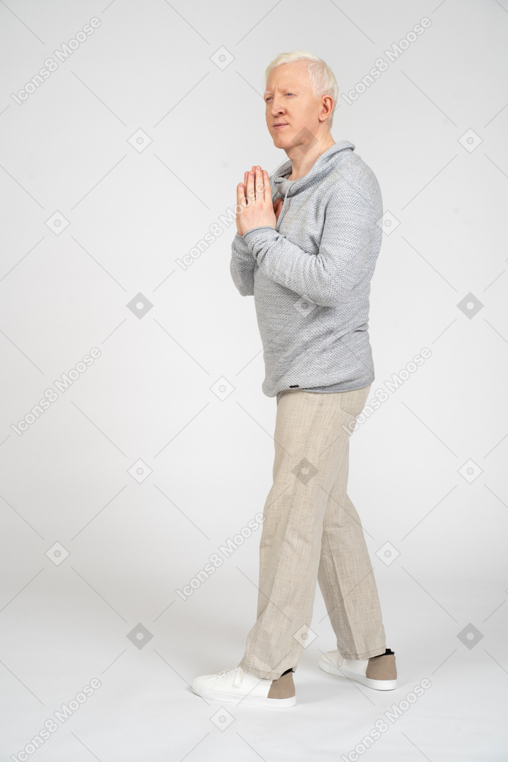 Man standing sideways and holding palms together