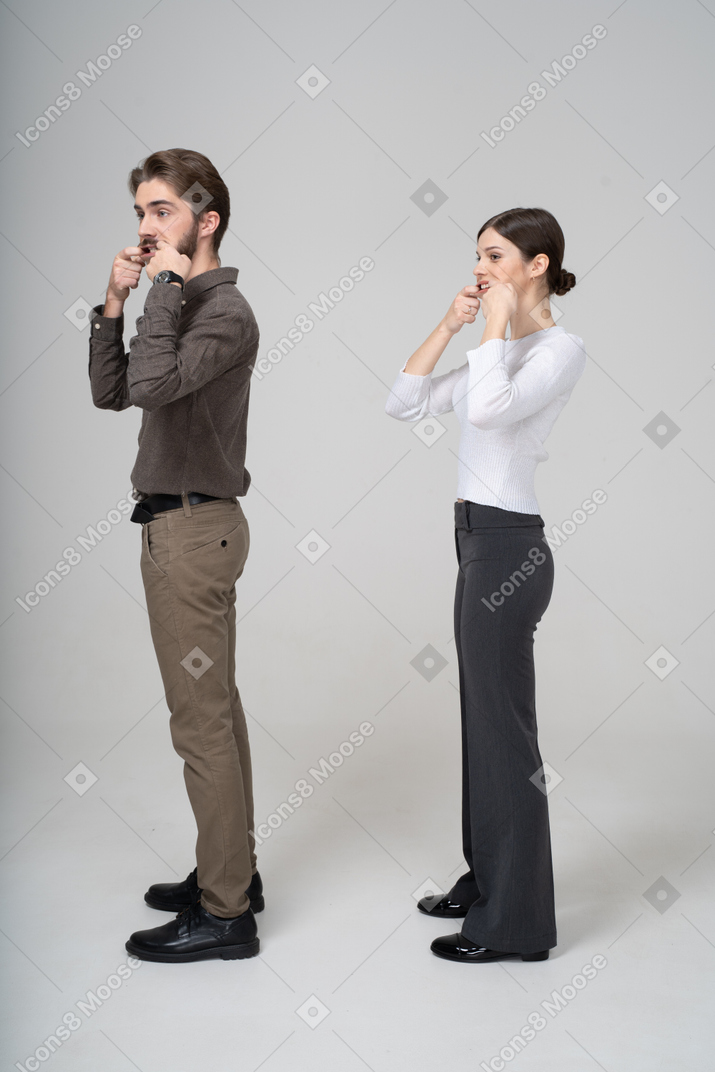Vista lateral de um jovem casal com roupas de escritório esticando a boca