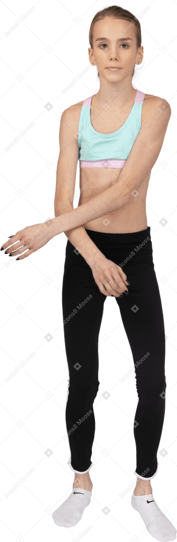 Vista frontal de uma adolescente em roupas esportivas cruzando as mãos enquanto olha para a câmera