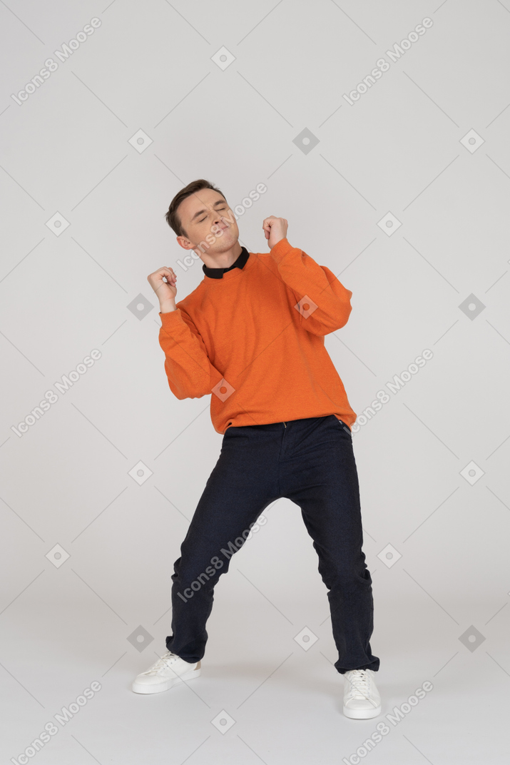 Молодой человек в оранжевой толстовке позирует