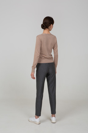 Back view of a young lady in pullover and pants turning away