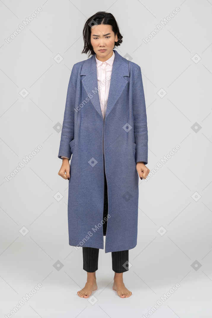 Donna arrabbiata in cappotto in piedi con i pugni chiusi