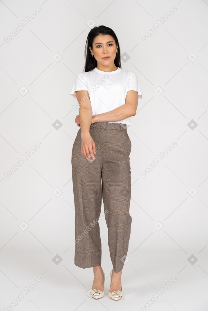 Front view of a thoughtful young woman in breeches putting hand on stomach
