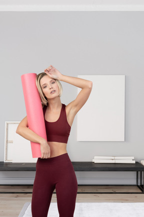 A woman holding a yoga mat in a room