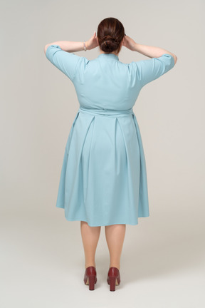 손으로 눈을 덮고 있는 파란 드레스를 입은 여성의 뒷모습