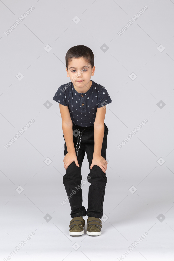 Vue de face d'un garçon mignon accroupi et touchant les genoux