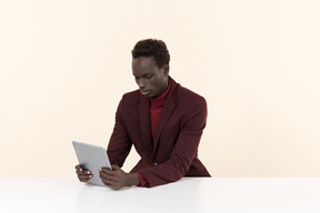 Elegante hombre negro sentado a la mesa en la oficina