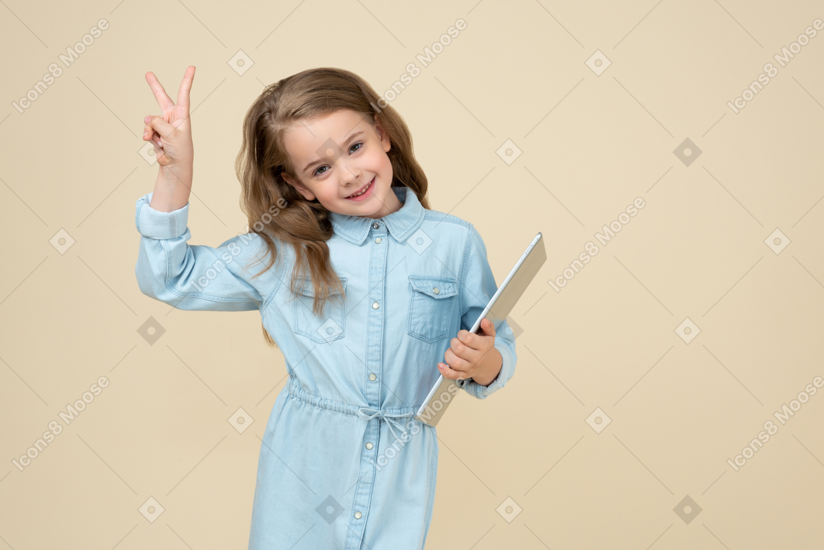 Cute little girl holding a tablet and showing v sign