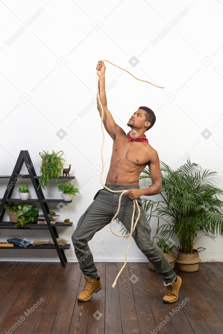 Strong young man raising his arm and throwing a rope