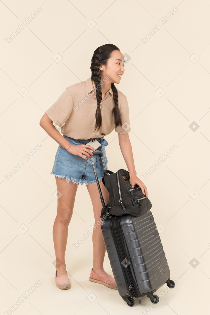 Viaggiatore femminile allegro che tiene i suoi bagagli
