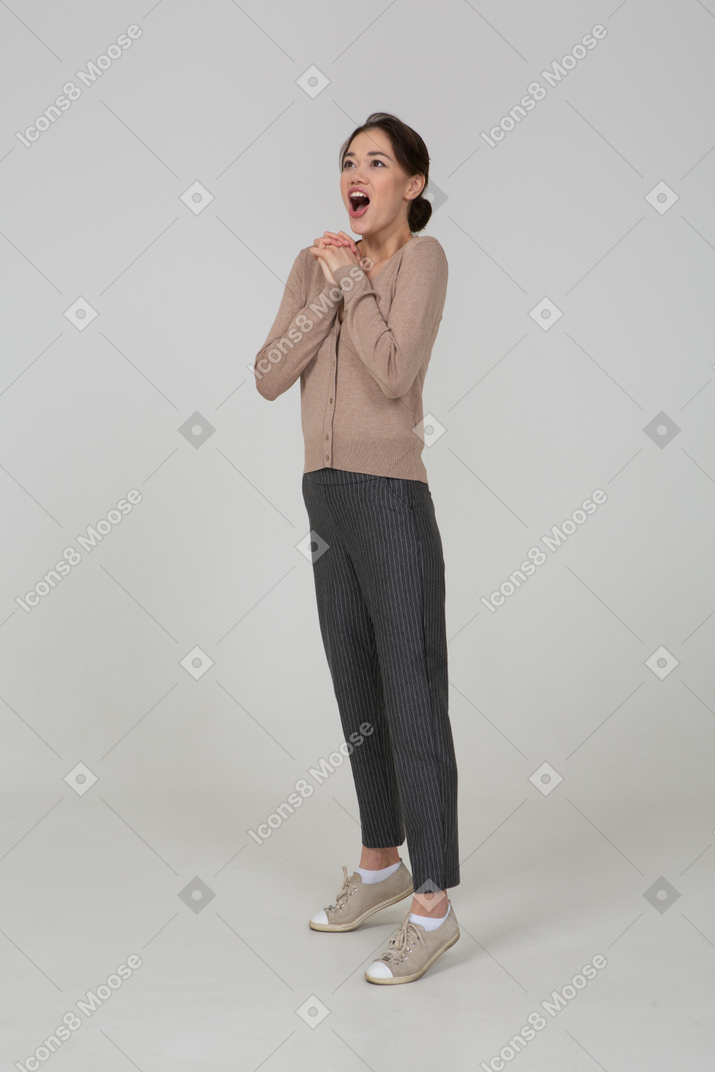 Three-quarter view of a delighted young lady in beige pullover holding hands together