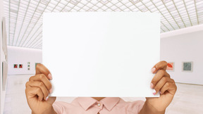 A person holding up a white piece of paper in front of their face