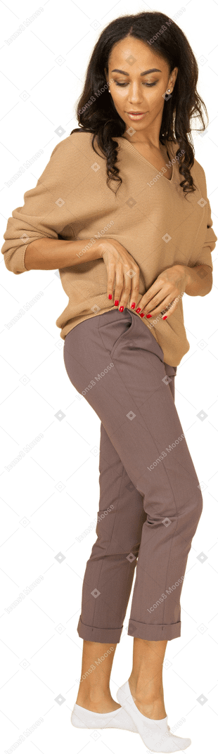Vista lateral de una mujer joven de piel oscura enrollando su pulóver