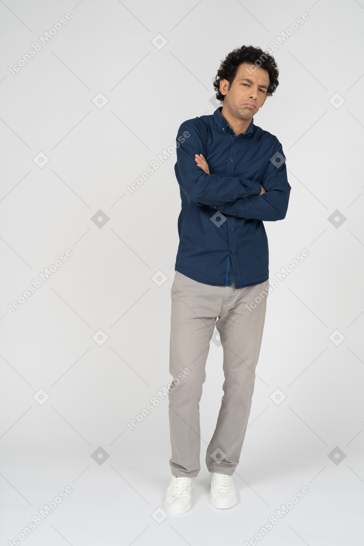 Vista frontal de un hombre serio en ropa casual posando con los brazos cruzados.