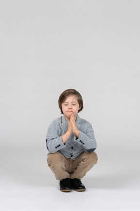 A young boy meditating in a squatting position