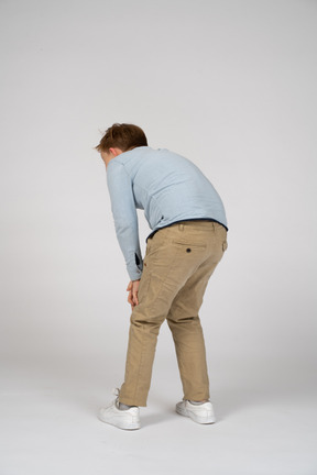 Back view of a boy bending down and touching knees