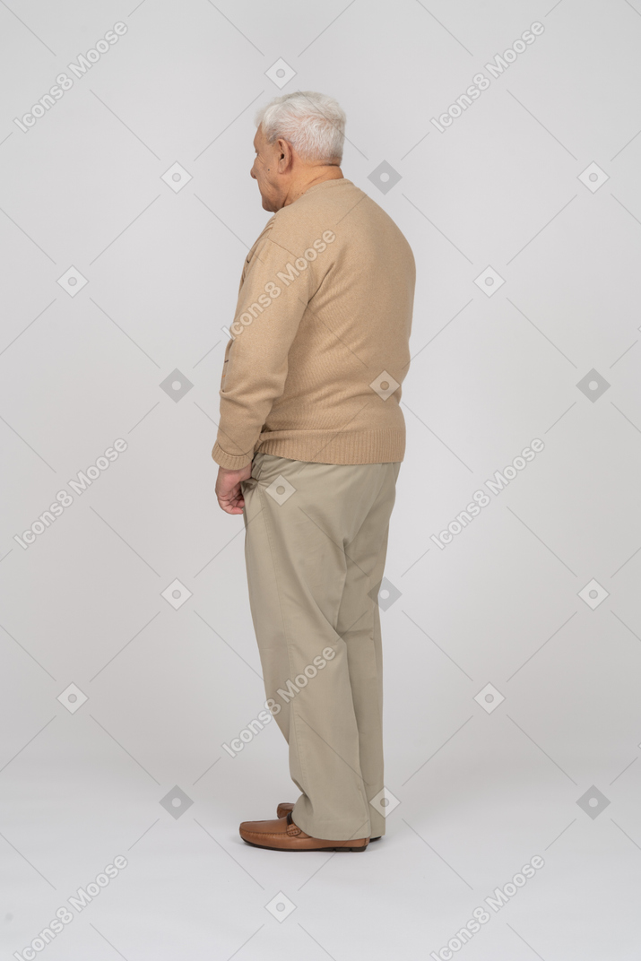 Vista lateral de um velho em roupas casuais em pé com as mãos nos bolsos