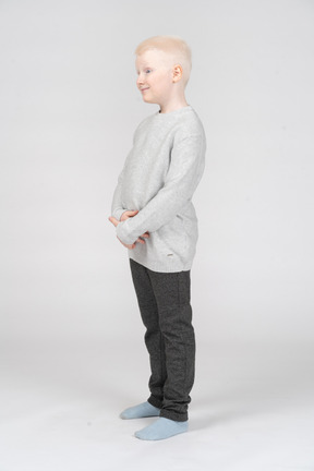 Full-length of a cute blonde male child touching his belly